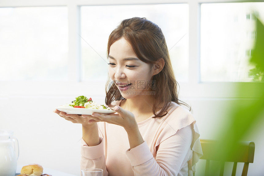 捧着一盘沙拉微笑的年轻女性图片