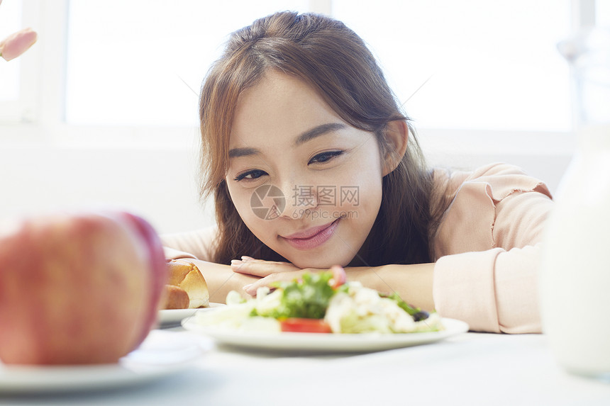 趴在餐桌上看着食物的女青年图片