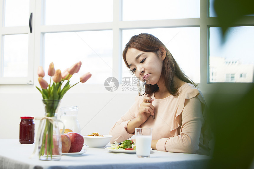 餐桌上拿着叉子的女青年图片