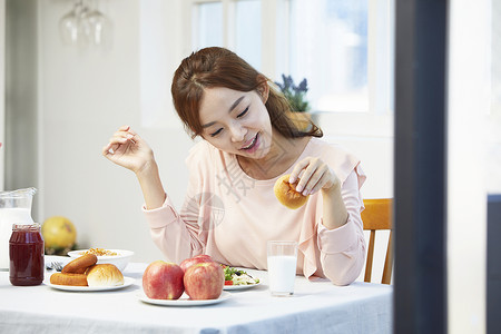 餐桌上拿着面包的女青年图片