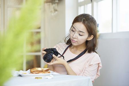 给美食拍照的年轻女子图片