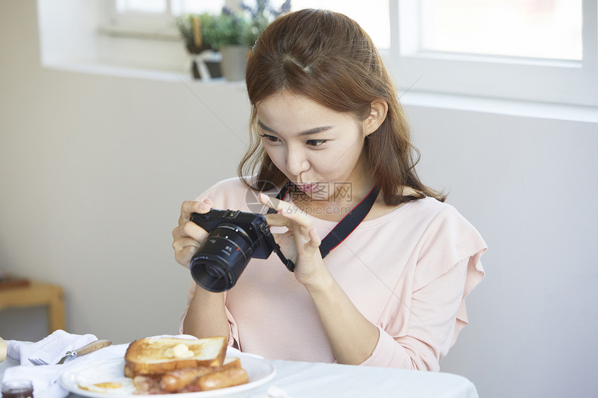 拿着数码相机拍食物图片的女青年图片