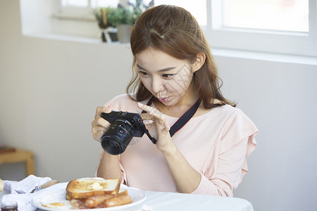 拿着数码相机拍食物图片的女青年图片