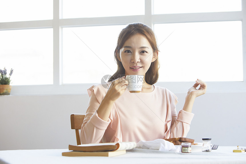 看着咖啡杯微笑的年轻女性图片