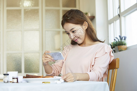 年轻女子拿着手机拍照图片