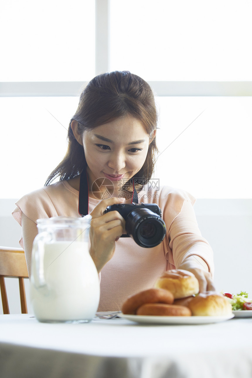 给食物进行拍照的年轻女孩图片