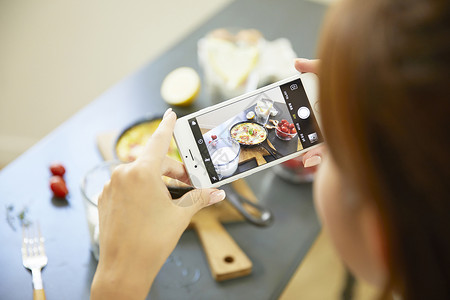年轻女子手机拍摄食物图片图片