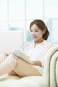 坐在沙发上使用笔记本电脑的年轻女性图片