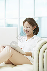 客厅沙发上使用笔记本电脑开心的年轻女子图片