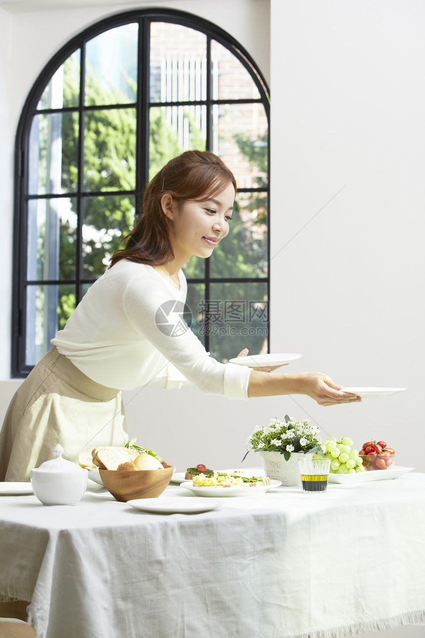 餐桌上摆放餐具的居家女性图片