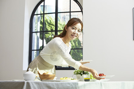 餐桌上摆放餐具的成年女子图片