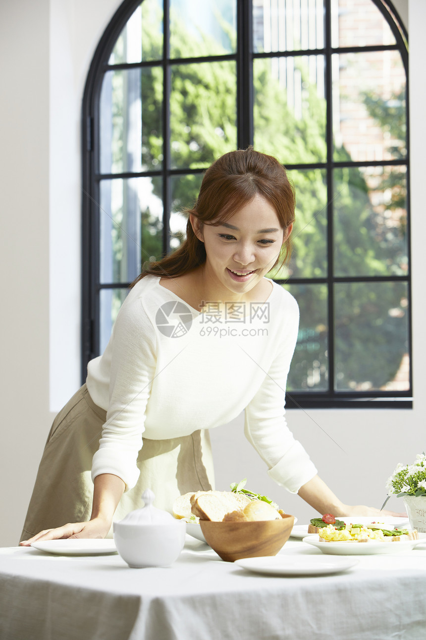 餐桌上摆放餐具食物的年轻女子图片