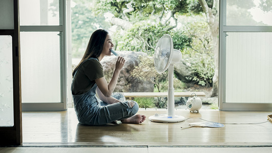 夏天坐着在家吹风扇吃冰棍的妇女图片