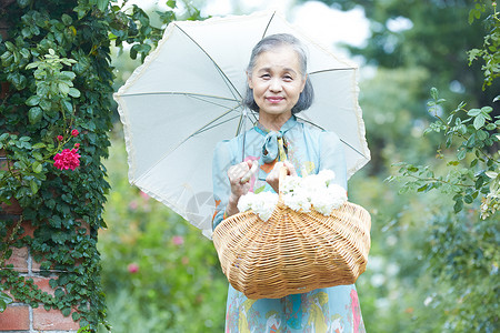 单人园艺老人拿着遮阳伞的资深妇女在庭院里图片