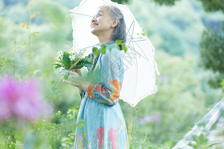 撑伞避暑姑娘在院子里撑伞的老年阿姨背景