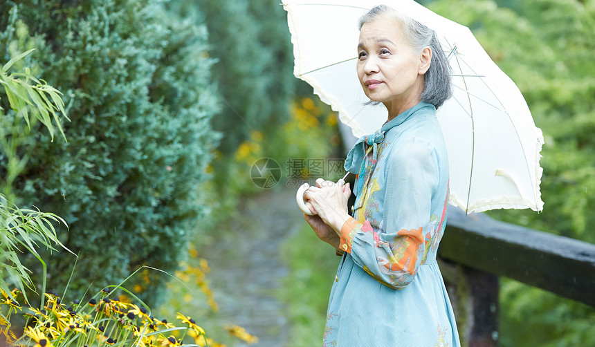 通路长辈60多岁拿着遮阳伞的资深妇女在庭院里图片
