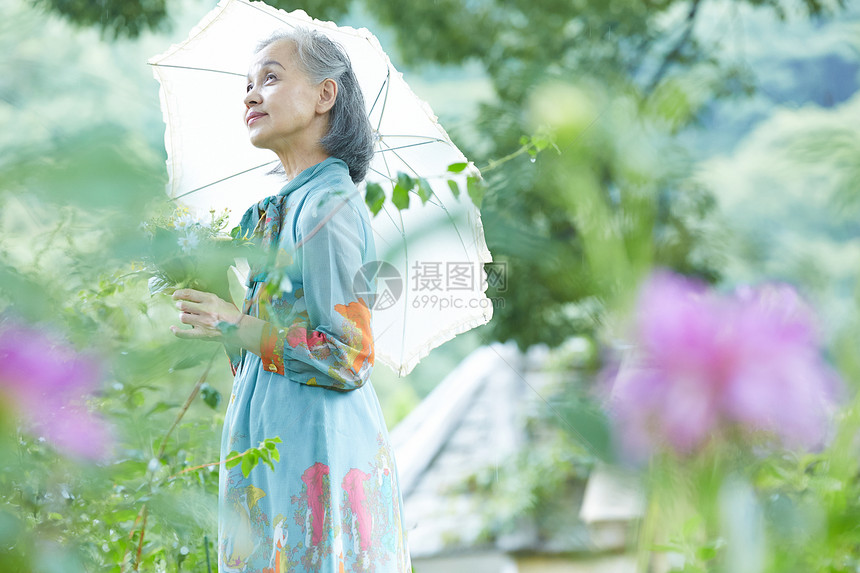 在庭院里拿着遮阳伞的老妇人图片
