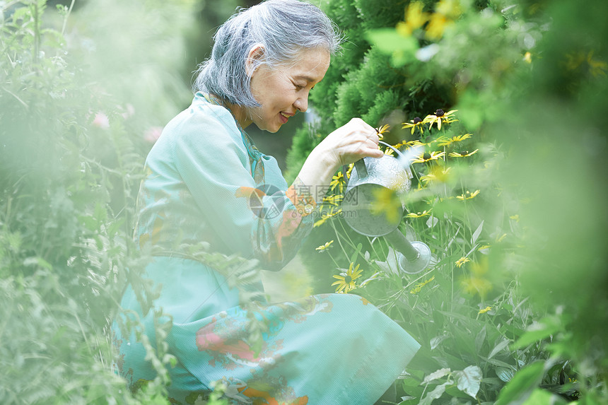 庭院里浇水的年轻女性图片