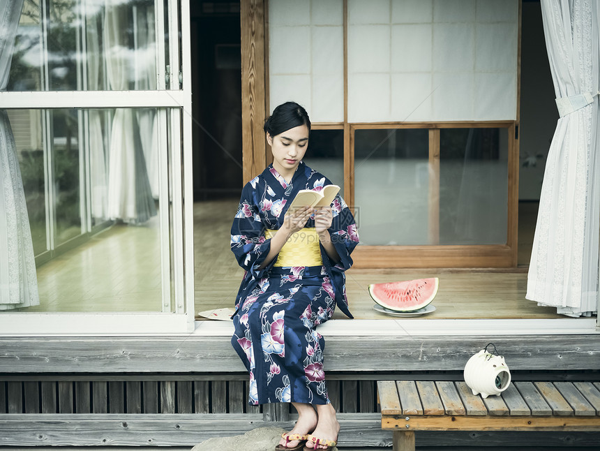 穿着日式和服坐在屋外看书的少女图片