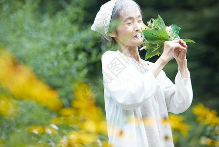 庭院里闻着花束的老年女性图片