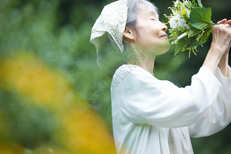 闭眼嗅闻花束的老年女性图片