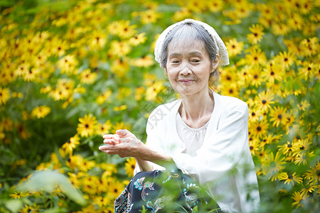 老年妇女在庭院花海里图片