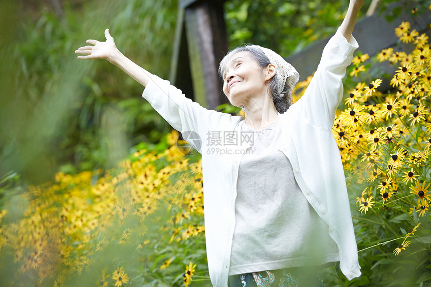 院子植物的自然放松的老年妇女图片