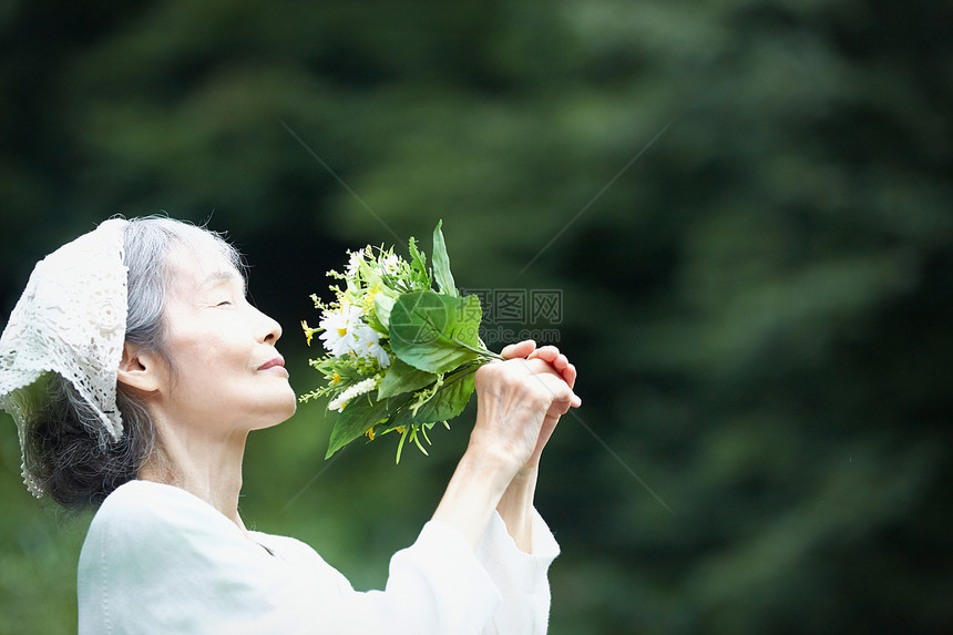 闻到花的气味的老年妇女图片