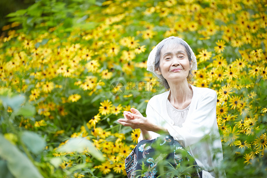 院子植物的自然放松的老年妇女图片