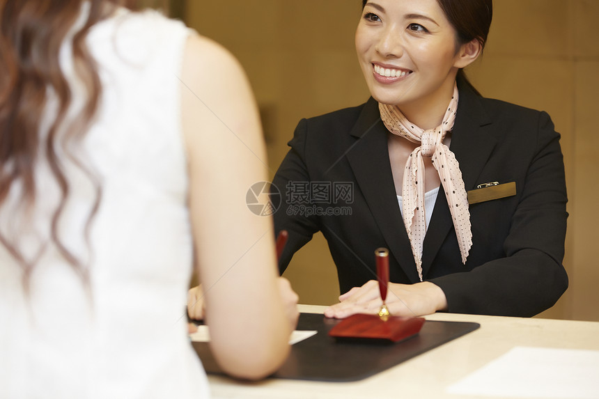 解释商务招待在酒店接待处工作的女人图片