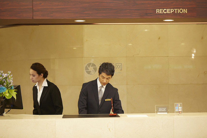 站立旅馆女士们在酒店接待处工作的男人和女人图片