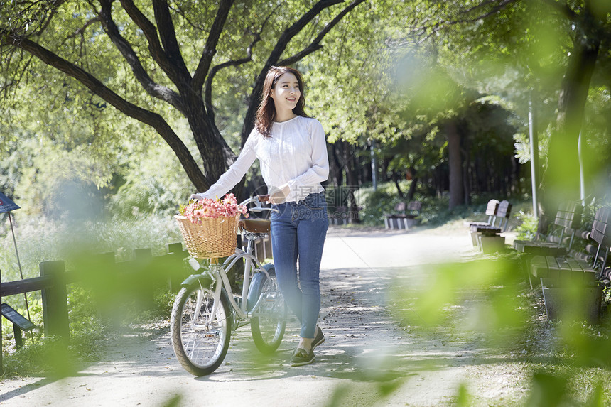 春天公园郊游推着自行车的年轻女子图片