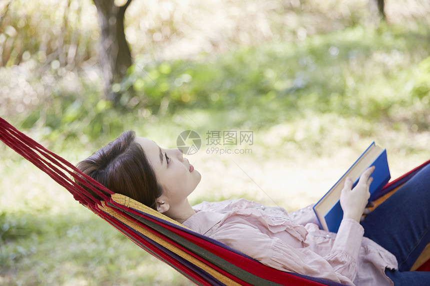 公园吊床上阅读的成年女性图片