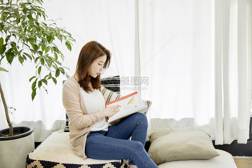 垫子上拿着书本的年轻女子图片
