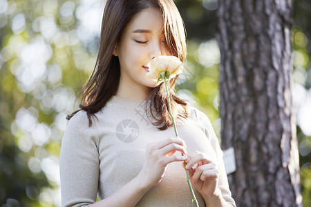低头嗅闻花朵的年轻女性图片