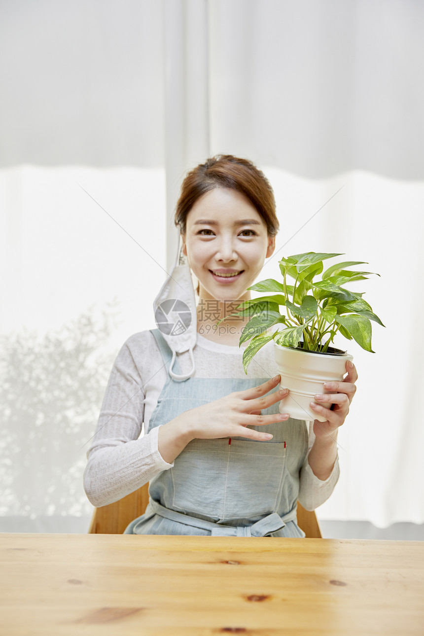 捧着植物盆栽微笑的女性图片
