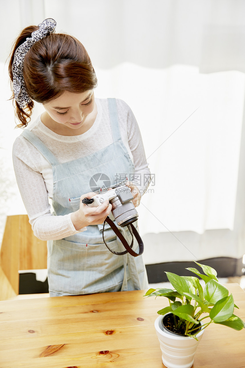 拿着相机拍植物照片的女性图片