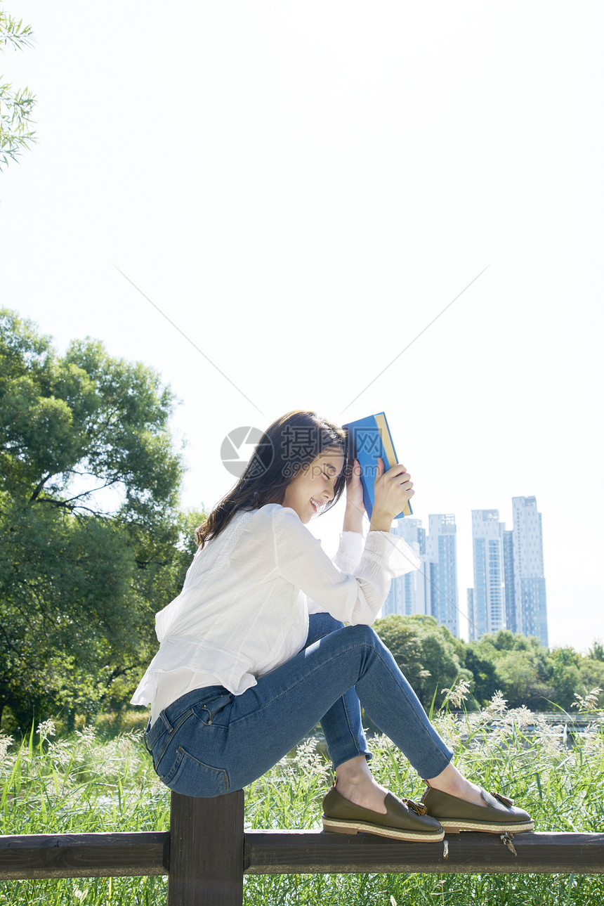 拿着书本遮挡阳光的女性图片