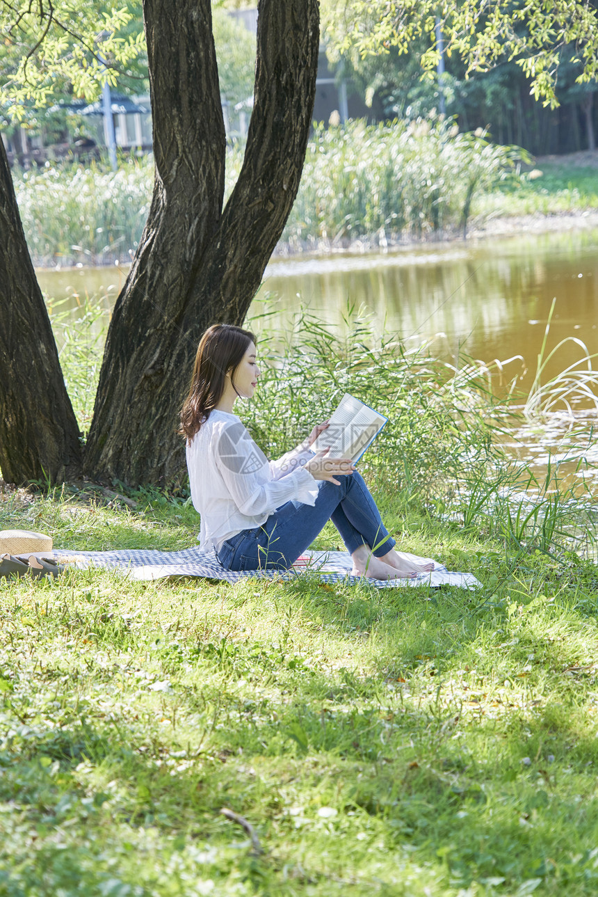 公园草坪上阅读的年轻女性图片