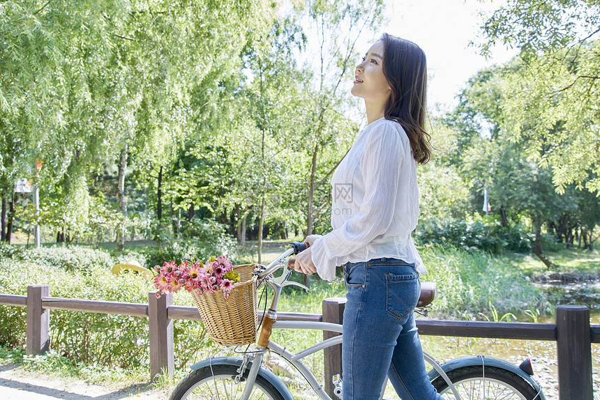 公园里推着自行车散步的女青年图片