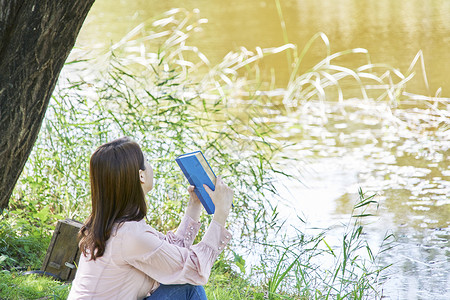 公园小河边看书的女性图片