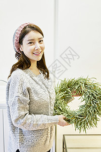 拿着树叶花环微笑的年轻女子图片