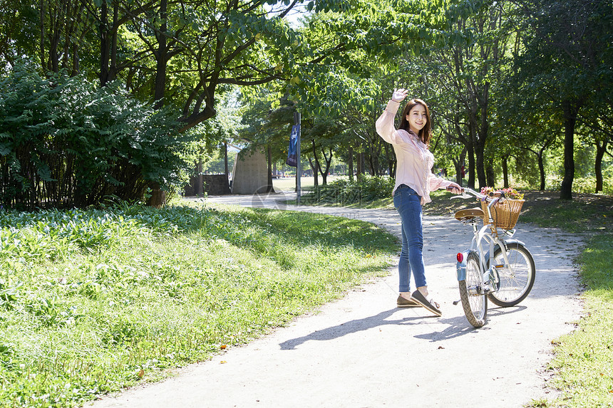 推着自行车招手的年轻女性图片