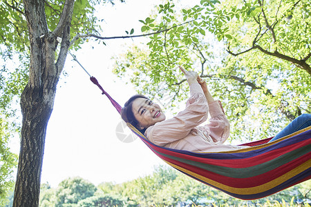 躺在吊床上玩手机的成年女子图片