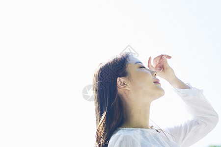 阳光下闭上眼睛的女性图片