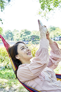 吊床上玩手机开心的女性图片