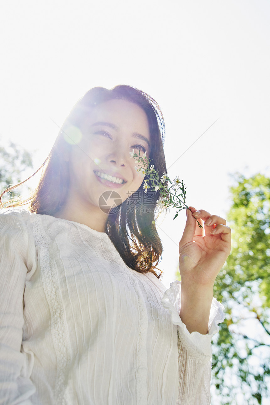 拿着花朵微笑的女性图片