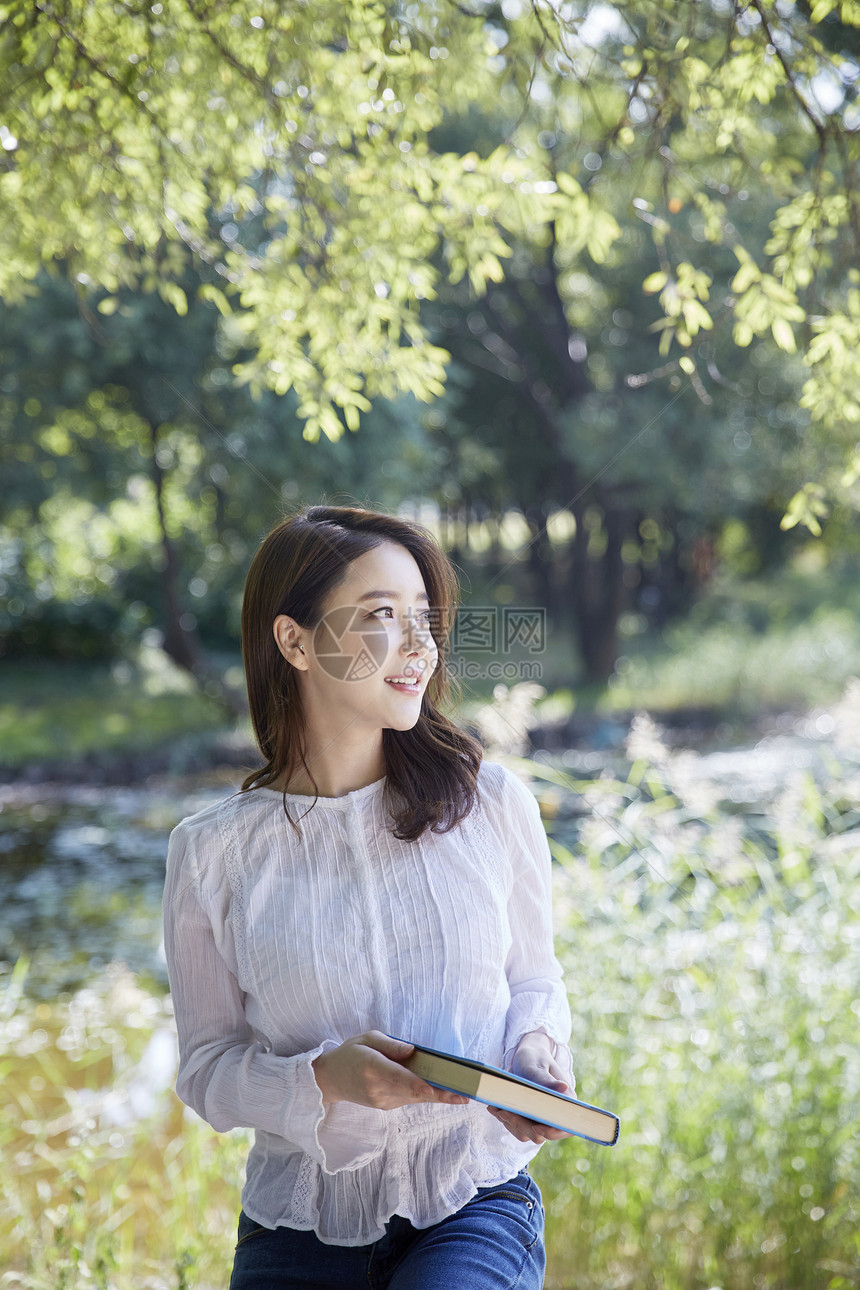 公园里拿着书的年轻女大学生图片