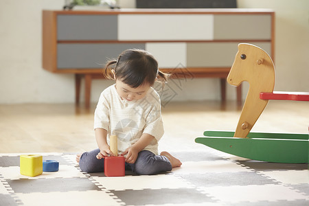坐在垫子上玩积木的小女孩图片