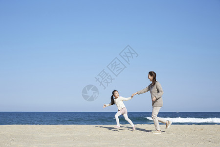 假期海边的母女旅行牵手奔跑图片